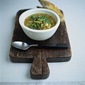 Bean and spinach soup with bread on a wooden board