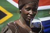 Frau trinkt ein Glas Rotwein vor südafrikanischer Fahne