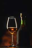 A glass and a bottle of cognac