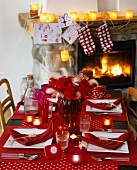 Christmas table laid in red in front of fireplace