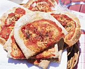 Several pizza breads on wicker tray on picnic table