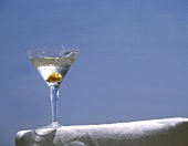 Glas Martini auf weisser Stuhlarmlehne vor blauem Himmel
