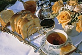Cup of tea, teapot, toast, jam and bouquet of roses