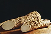 Two horseradish roots on wooden plate