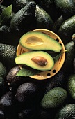 Avocados, darauf Teller mit zwei Avocadohälften