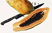 Eine Papaya, in die Hälfte geschnitten mit Kernen & Messer