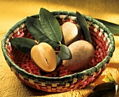 Whole and half sapodilla with leaves in a basket