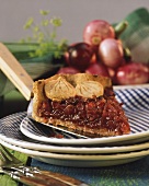 A piece of red onion tart with pastry onion decoration