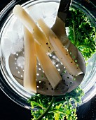 Scorzonera on straining spoon and kale in iced water