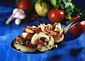 A spoonful of spicy pasta salad with chili and pine nuts