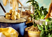 Polenta dumplings on ladle above pan, pine nuts, basil