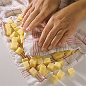Drying raw potato cubes in kitchen cloth