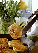 Potato cakes (in the pan and on fork) with salad