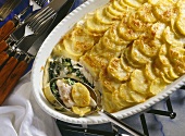 Potato and fish casserole with spinach in baking dish