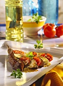 Baked aubergines with tomatoes on white baking sheet