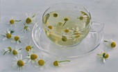 Camomile tea in glass cup and camomile flowers