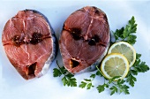 Zwei rohe rote Thunfischsteaks mit Zitronen und Petersilie