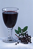 Elderberry juice in glass, a few elderberries beside it