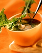 Broad bean soup with dandelion in orange bowl