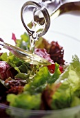 Öl über Salatlöffel auf gemischten Salat gießen