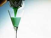 Grasshopper Cocktail mit Minzlikör aus Shaker in Glas gießen