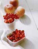 Raspberries in plastic box, strawberries, redcurrants in beaker