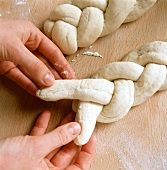 Forming rolls: hands plaiting strands of dough