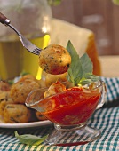 Bread balls on plate and fork above tomato sauce