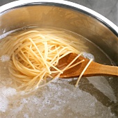 Cooking spaghetti; stirring in water with wooden spoon