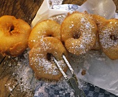 Apple fritters with icing sugar on wooden background