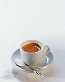 Espresso in white cup; sugar on spoon and beside cup