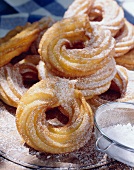 Sugared doughnuts on wooden plate; sieve with icing sugar
