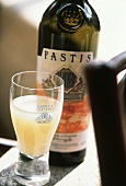 A glass of pastis in front of bottle on table