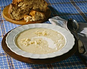 Sauerkraut soup with sour cream; farm bread on wooden plate