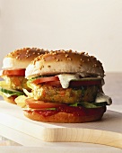 Vegetable burger with tomatoes, cucumber etc on chopping board 