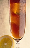 Iced tea with lemon in tall glass with drops of water