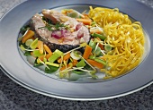 Salmon cutlet on vegetables with ribbon pasta on plate