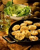 Baked potatoes with cheese, caraway & sesame in pan; salad