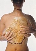 Honig als Schönheitsrezept - Frau hält Wabe vor ihren Körper