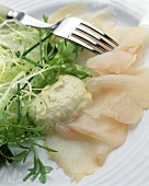 Fish carpaccio with sauce and endive on a plate