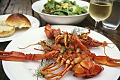 Boiled yabby with salsa on plate; salad; wine