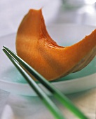 A slice of pumpkin on glass plate and two chopsticks