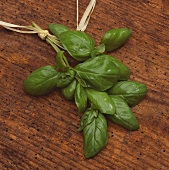 A bunch of basil with drops of water on wooden background