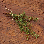 A bunch of thyme with drops of water on wooden background