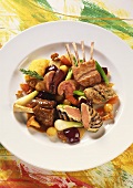 Various parts of kid with braised vegetables on plate