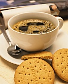 A cup of black coffee & a few biscuits; decoration: newspaper