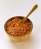 Red lentils in a small bowl with a wooden spoon