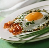 Herbed fried egg with bacon and chives on plate