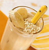 Thick banana shake with oat flakes and banana slices 