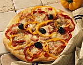 Pepper pizza with black olives on stone background